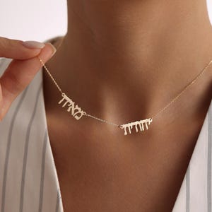 May include: A gold necklace with two Hebrew words, "אהבה" and "שלום", hanging from a delicate chain.
