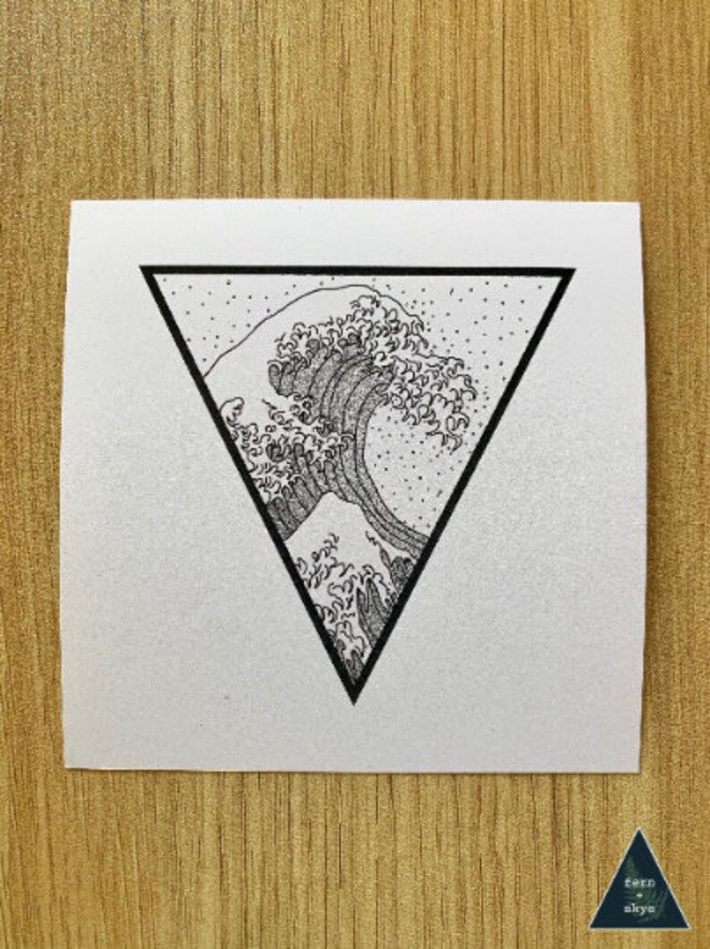 May include: A black and white illustration of a wave, enclosed within a black triangle. The artwork is reminiscent of the iconic Great Wave off Kanagawa. The image is on a white square, with the text "fern + akye" in a small triangle in the bottom right corner.