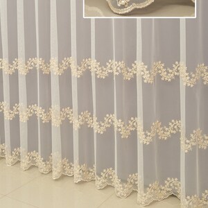 Puede incluir: Cortinas blancas de voile con un delicado ribete de encaje floral. El encaje presenta pequeñas cuentas de imitación de perlas y un borde festoneado.