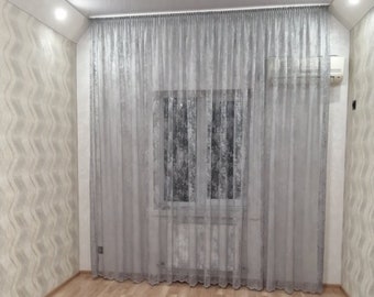 May include: A room with white walls and a light wood floor. A window with white sheer curtains is in the centre of the wall. The curtains are drawn and the window is covered with a white sheer curtain.