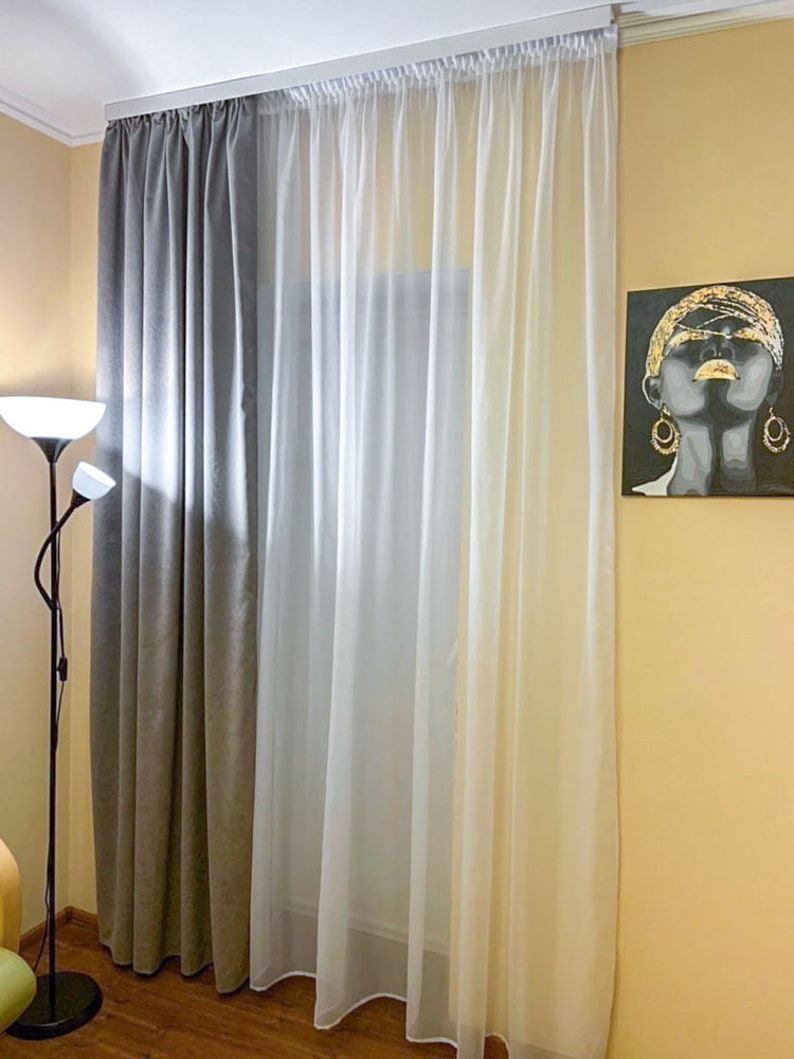 May include: Gray and white curtains hanging in a window. The curtains are lined up next to each other. The gray curtains are on the left and the white curtains are on the right.