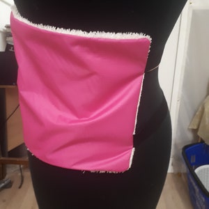 May include: A pink fabric panel with a white frayed edge is attached to a black dress form.