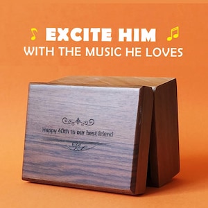 May include: A wooden music box with the text "EXCITE HIM WITH THE MUSIC HE LOVES" and "Happy 40th to our best friend" engraved on the front. The box is brown and has a rectangular shape.