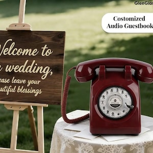 May include: A burgundy rotary dial telephone sits on a lace-covered table. The phone is connected by a coiled cord. A wooden sign with the words "Welcome to our wedding" is in the background. The text "Costomized Audio Guestbook" is also visible.