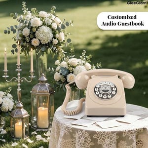 May include: A cream-coloured vintage rotary phone on a lace-covered table, with the text "Customized Audio Guestbook". The scene includes floral arrangements, lit candles, and lanterns, suggesting a wedding or event setting.