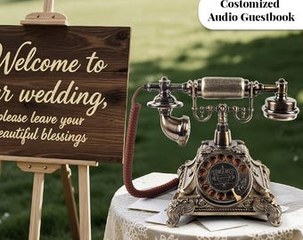 May include: An antique-style telephone with a rotary dial and ornate detailing sits on a lace-covered table. The phone is bronze-colored and has a coiled cord. A wooden sign with the words "Welcome to our wedding" is in the background.
