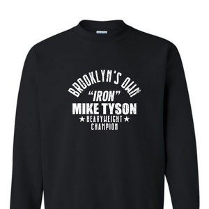 May include: Black sweatshirt with a white graphic print that reads "Brooklyn's Own "Iron" Mike Tyson Heavyweight Champion".
