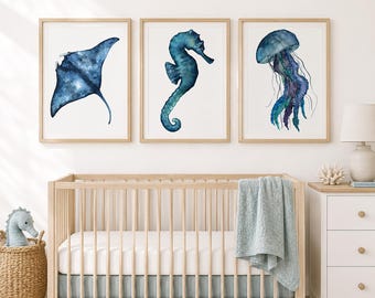 May include: Three framed wall art prints featuring watercolor illustrations of marine life. The left print shows a dark blue manta ray, the center print depicts a teal seahorse, and the right print displays a blue and purple jellyfish.