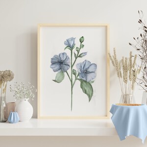 May include: A watercolor painting of blue flowers with green leaves in a light wood frame. The painting is on a white shelf with a vase of white flowers and a blue vase.