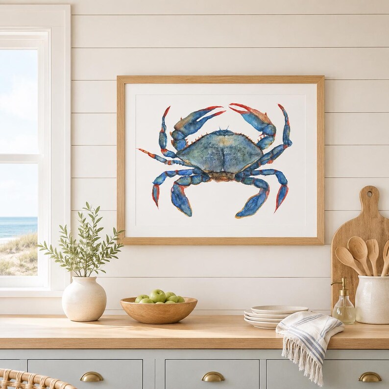 May include: A framed watercolor print of a blue crab with a mottled blue and green shell and bright red-tipped claws. The artwork is displayed in a light-toned wooden frame, showcasing the detailed brushstrokes and vibrant colors of the crustacean.