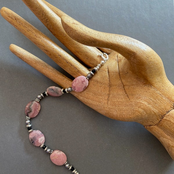 Rhodonite bracelet featuring flat oval beads accented with tiny grey glass pearls and faceted onyx beads