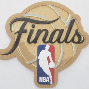 May include: A gold-colored patch featuring the word Finals in black script lettering overlaid on a basketball graphic. Below the text is the red, white, and blue NBA logo with a white silhouette of a basketball player dribbling a ball.