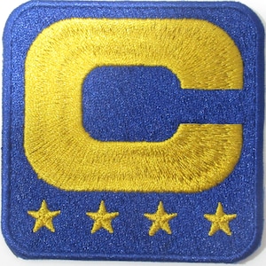 Könnte beinhalten: Gestickter Aufnäher mit einem goldenen Buchstaben C und vier goldenen Sternen auf blauem Hintergrund.