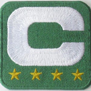 Peut inclure: Patch en feutre vert avec une lettre C brodée en blanc et quatre étoiles brodées jaunes.