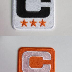 May include: Two embroidered patches, one white with a black "C" and four orange stars, the other orange with a white "C" and four gold stars.
