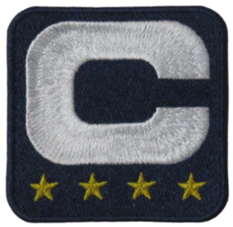 May include: Embroidered patch with a navy blue background. A large, white, capital letter "C" is centered, with a white embroidered outline. Four gold stars are embroidered along the bottom edge. The patch is square with rounded corners.