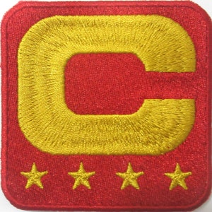 Peut inclure: Écusson brodé rouge et or avec un grand C et quatre étoiles dorées.
