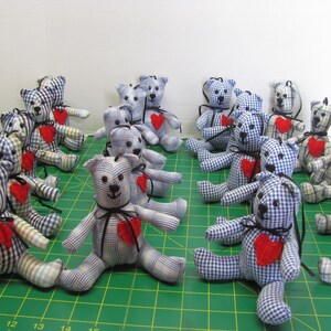 May include: A group of 15 blue and white plaid teddy bears with red felt hearts sewn on their chests. The bears are arranged in rows on a green cutting mat.