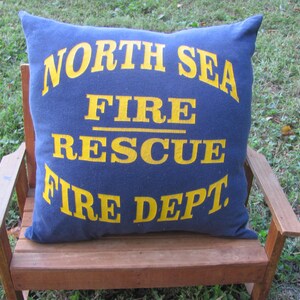 May include: A blue pillow with yellow text that reads "North Sea Fire Rescue Fire Dept."
