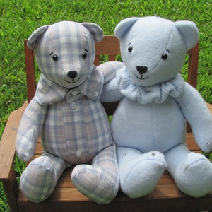 May include: Two handmade teddy bears sitting on a wooden bench. The bear on the left is made from a blue and white plaid fabric and has a button-up shirt collar. The bear on the right is made from a light blue fabric and has a ruffled collar.