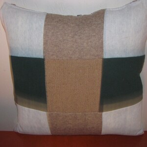May include: A patchwork pillow with a brown, white, and green color scheme. The pillow is made of different fabrics, including a herringbone pattern.