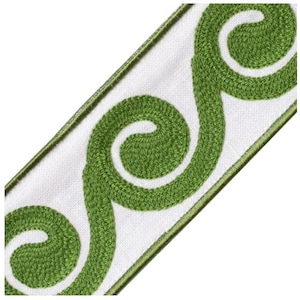 May include: White fabric ribbon with a green embroidered swirl design. The ribbon has a green border and a textured appearance. This decorative trim is suitable for various craft projects.