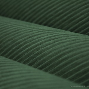 May include: Close-up of a deep green corduroy fabric with a ribbed texture. The fabric is folded in thirds, creating a layered effect.