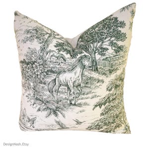 May include: A white pillow with a green and white horse and tree design. The design is reminiscent of a toile pattern.