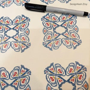 May include: Cream-colored fabric with a repeating pattern of stylized floral designs in blue, red, and yellow. A black Sharpie marker rests on the fabric. The Etsy shop name, DesignNash.Etsy, is visible.