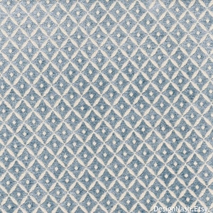 May include: Close-up of a textured fabric with a repeating diamond pattern. The diamonds are a muted blue color, outlined in a lighter cream color. The fabric has a soft, plush appearance, suitable for upholstery or home decor.