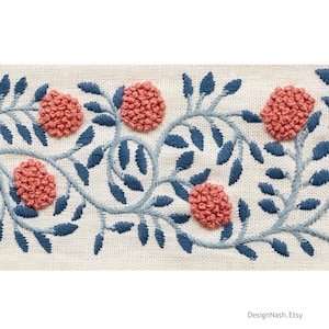 May include: Close-up of embroidered fabric featuring a floral design. The design includes coral-colored, textured flower-like shapes and dark blue leaves and vines on a cream-colored background. The Etsy shop name, DesignNash.Etsy, is in the bottom right corner.