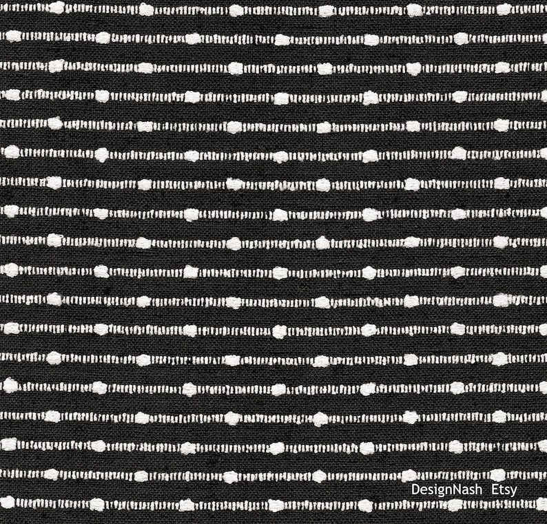 May include: Black and white striped fabric with a textured surface. The fabric has a repeating pattern of white dots on black stripes.