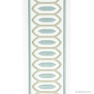 May include: White fabric with a blue and beige embroidered border. The border features a repeating pattern of oval shapes.