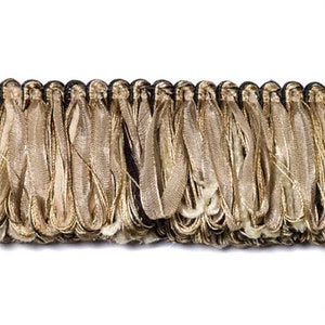 May include: A close-up of a gold and beige fringe trim with a black backing. The fringe is made of a variety of materials, including silk and metallic threads.