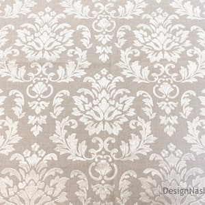 Peut inclure: Tissu beige avec un motif damass&eacute; blanc. Le motif pr&eacute;sente un dessin r&eacute;p&eacute;titif de fleurs et de feuilles stylis&eacute;es.