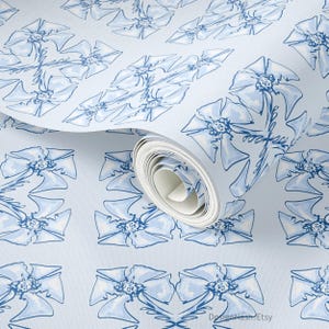 May include: Light blue wallpaper roll featuring a repeating pattern of stylized blue flowers. The floral design has a watercolor effect, with delicate lines and shading. The roll is partially unrolled, revealing the pattern.