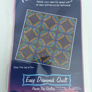 May include: A quilting pattern package titled "Fun & Done! Quilting" with the text "Easy Diamonds Quilt." The package features a blue background with a geometric diamond pattern in orange, green, and blue. Sizes include crib, lap, or twin.