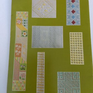 May include: A green paper featuring several needlepoint designs in white, yellow, red, and blue. The patterns include geometric shapes, floral designs, and diamond patterns. The paper has a vintage aesthetic.
