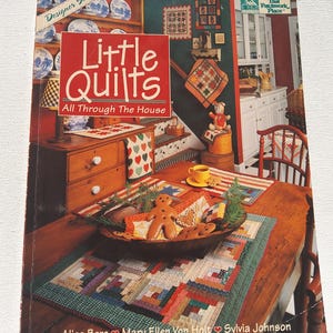 May include: A book titled "Little Quilts All Through The House" with a red cover. The book features images of quilts and home decor. The cover also includes the names Alice Berg, Mary Ellen Von Holt, and Sylvia Johnson.