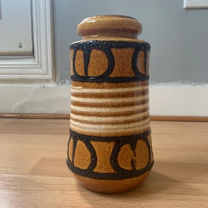 Peut inclure: Un vase en céramique brun et noir avec un motif géométrique. Le vase a une base large et un col étroit.