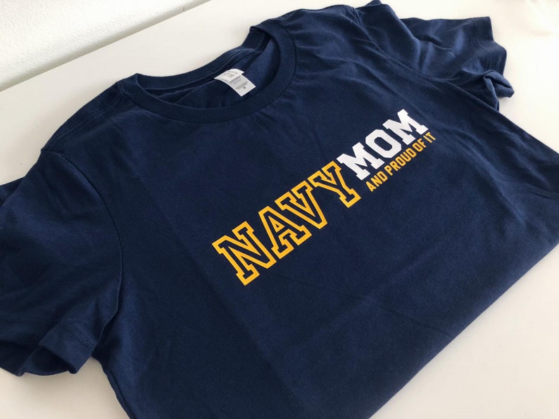 May include: Navy blue t-shirt with yellow lettering that reads "NAVY MOM AND PROUD OF IT".