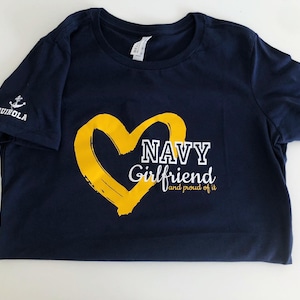 May include: Navy blue t-shirt with a yellow heart and the text "NAVY Girlfriend and proud of it".