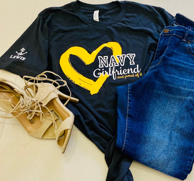 May include: A black t-shirt with a yellow heart and the text "NAVY Girlfriend and proud of it".
