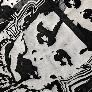 May include: Black and white abstract pattern on a fabric surface. The pattern is made up of lines, circles, and other shapes.