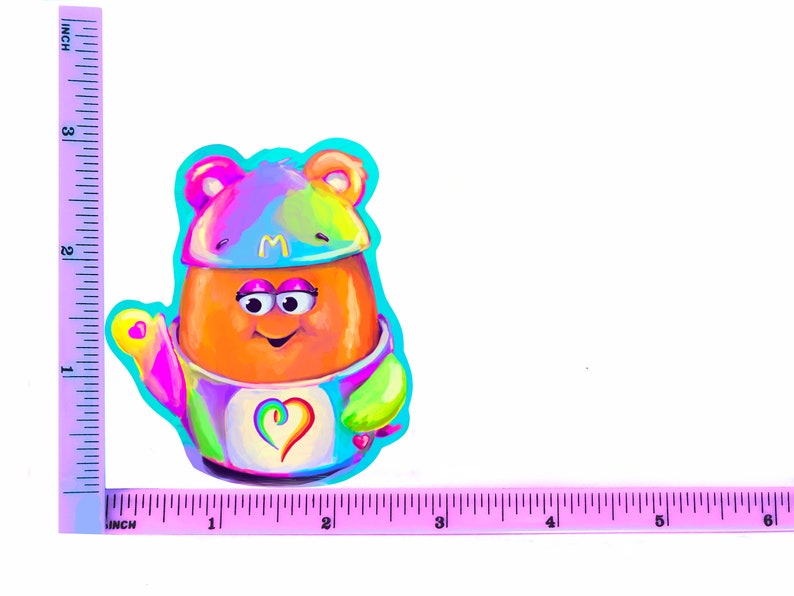 May include: A colorful cartoon character with a rainbow-colored hat and a heart on its chest. The character is wearing a blue and green outfit and has a big smile.