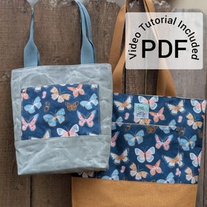 May include: Two tote bags with butterfly print fabric. The smaller bag is light blue with a pocket and the larger bag has a brown bottom and a blue butterfly print. The text "Video Tutorial Included PDF" is on a white circle.