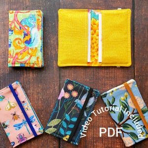 Può includere: Una collezione di porta carte e portafogli in tessuto con vari motivi. Uno è giallo brillante, aperto per rivelare fessure per carte. Altri presentano disegni floreali, di insetti e di scoiattoli. Il testo "Video Tutorial Included PDF" è visibile.