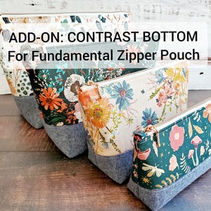 May include: Four zipper pouches with floral fabric and denim bottoms. The pouches are stacked on top of each other. The top pouch has a white background with colourful flowers. The second pouch has a dark green background with colourful flowers. The third pouch has a white background with colourful flowers. The fourth pouch has a dark green background with colourful flowers. The text "ADD-ON: CONTRAST BOTTOM For Fundamental Zipper Pouch" is displayed on a white background.