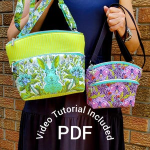 May include: Two crossbody bags. One is lime green and floral with a rabbit design, the other is purple with a butterfly pattern. Both have a zippered pocket and a black strap. The text "Video Tutorial Included PDF" is in the image.