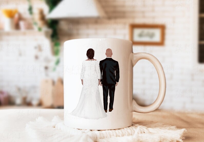 May include: A white ceramic mug featuring an illustration of a couple in wedding attire, holding hands. The bride is in a white gown, and the groom is in a black tuxedo. The mug has a curved handle.